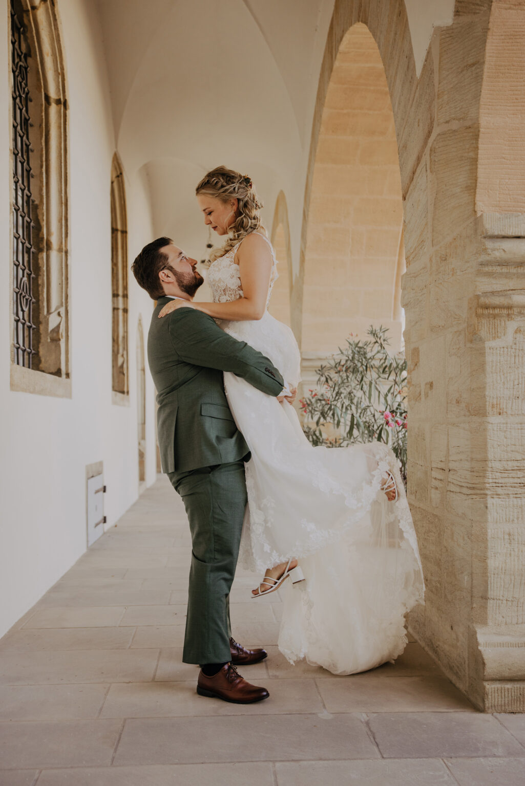 Bräutigam hebt Frau unter Bogengang, Hochzeitsplanung Foreva Weddings